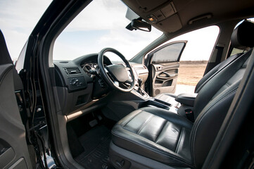Modern car interior, black perforated leather, aluminum, details controls, leather steering wheel.