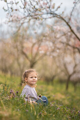 Little girl enjoying nice and sunny spring day near blooming apple tree in Prague park