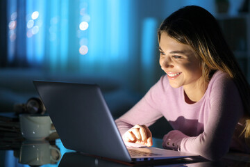 Happy woman watching media on laptop at home