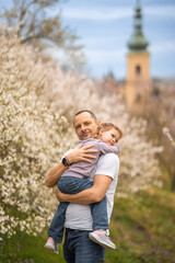 Fototapeta premium Father and daughter having a fun together under a blooming tree in spring park Petrin in Prague, Europe