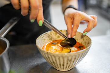 woman chef cooking Tom Yam soup on restaurant kitchen