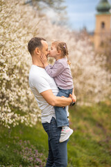 Father and daughter having a fun together under a blooming tree in spring park Petrin in Prague, Europe