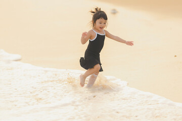 very happy time of cute girl in dress black run play on the beach with blur background beautiful sunset in the sea