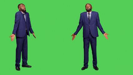 Corporate worker saying i dont know on camera and standing over full body greenscreen backdrop. Young startup employee in suit feeling unsure and confused, being uncertain in studio.