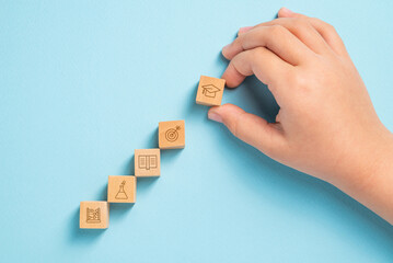 Student organizing wooden cubes with education icons. Education concept