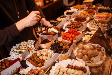 Sweets factory shop. Lots of different chocolates on store window. Hands holding plate of chocolates.