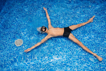 Little athletic boy trains to hold his breath underwater. Child dives with mask of blue pool water.