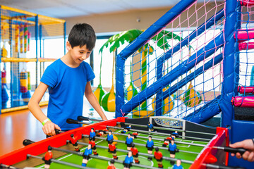 Little boy playing board football in children's play center. Hobbies and recreation.