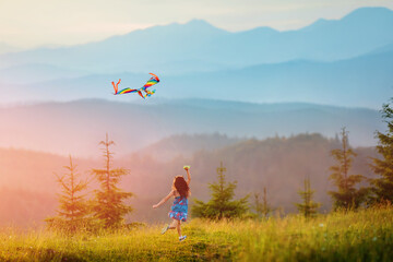 Little happy child girl running with kite. Wonderful mountain landscape in Alps at sunset. Travel, vacation alps.