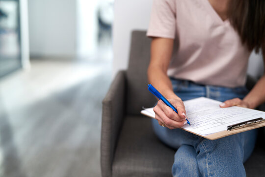 Woman with pen filling form sitting in waiting room