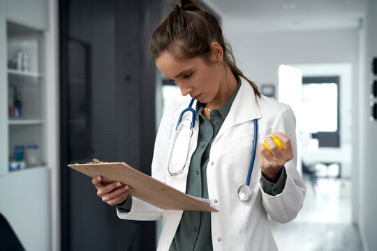 Female doctor with stress ball examining documents in clinic