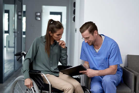 Doctor discussing with patient sitting in wheelchair