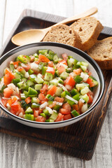 Summer Spanish Salad Pipirrana with green pepper, tomatoes, cucumber, onion and caraway closeup on the plate on the table. Vertical