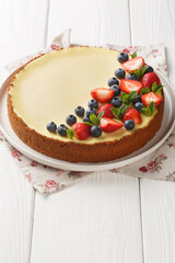 New York style classical cheese cake with fresh berries and mint closeup on the plate on the wooden table. Vertical