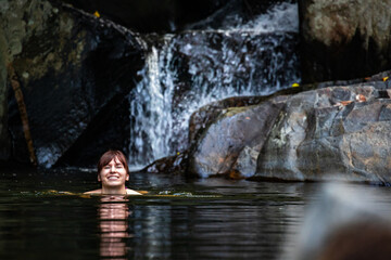 a beautiful girl in a bikini takes a refreshing swim at a waterfall at cedar creek swimming holes near brisbane and gold coast in queensland, australia; hidden gems of australia
