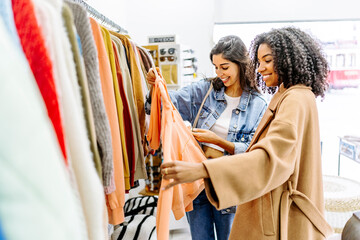 Happy young multiracial friends shopping together at clothing store
