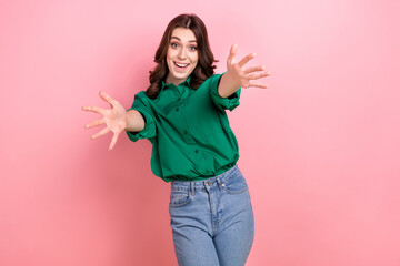 Photo of adorable friendly funny woman with wavy hairdo dressed green stretches out arms to embrace you shirt isolated on pink background