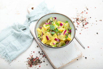 Delicious new potato salad with red onion, capers, greens in a bowl.