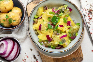 Delicious new potato salad with red onion, capers, greens in a bowl.
