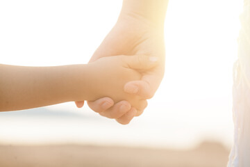 Child and parent hands on light background. Help, protection, family concept