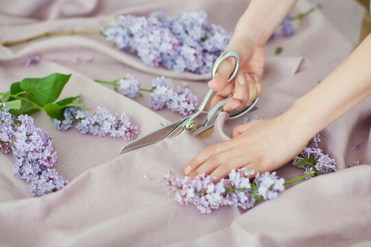 Hands of woman cutting linen fabric with scissors