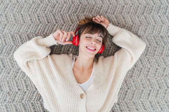 Carefree woman enjoying listening to music lying on floor at home