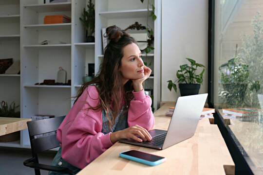 Thoughtful businesswoman sitting with laptop at cafe