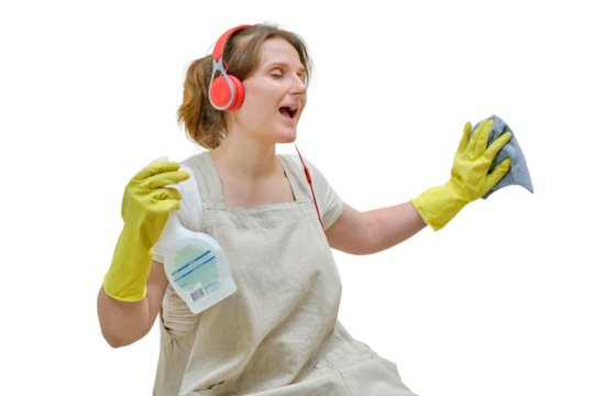 A happy woman with a rag in her hand and headphones sings while cleaning in the home kitchen, isolated on a white background