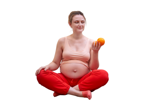 A pregnant woman exercises at home and holds a fruit in her hand as a symbol of healthy food during pregnancy, isolated on a white background