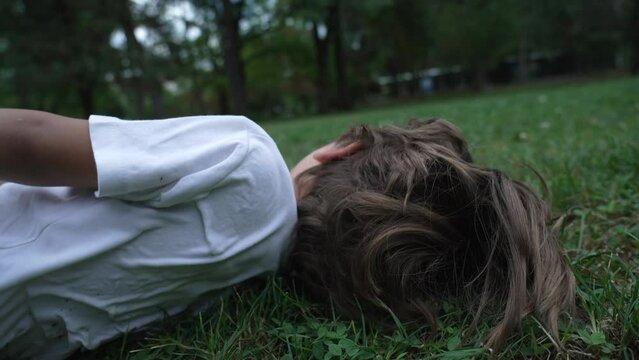 Happy child laughing close up face. Male kid laid on grass smiling. Real life laugh and smile. Authentic joy expression