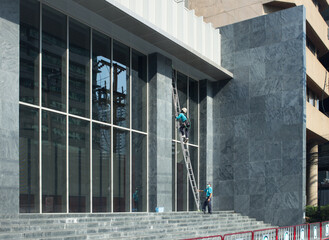 Professional workers with wash tools on mirror exterior Building panels.