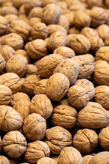 Shelled walnuts. Pile of unshelled walnuts in daylight. Walnut background.