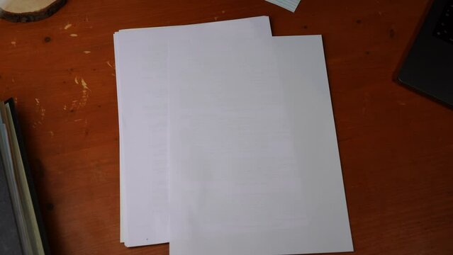 black permanent marker is taken by one hand from a desk on which paper also hangs a laptop and a folder