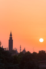 Fototapeta na wymiar Sunset over Cremona with the imposing silhouette of the Torrazzo, bell tower of the Cathedral in beautiful market square Piazza Duomo. Lombardy, Italy.