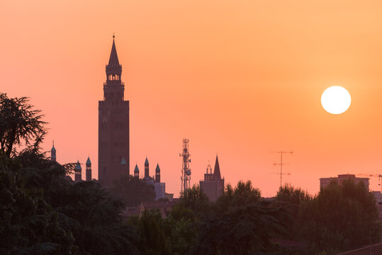 Sunset over Cremona with the imposing silhouette of the Torrazzo, bell tower of the Cathedral in beautiful market square Piazza Duomo. Lombardy, Italy.