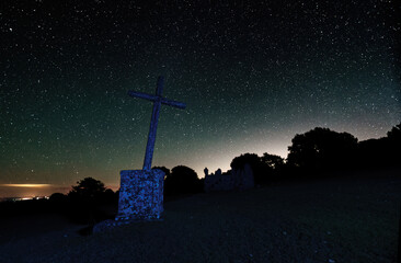 Obraz premium Long Exposure night photograph with stars in the background and foreground a cross and trees