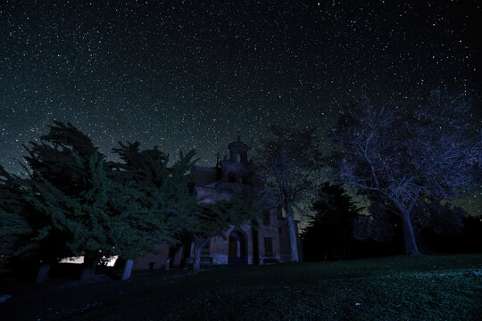 Long Exposure photography at night with stars in the background and foreground with a church and trees