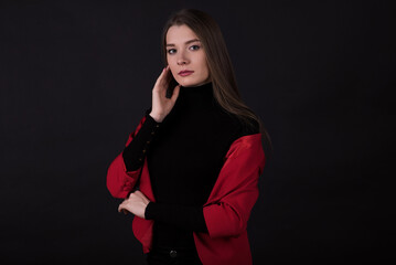 Portrait of a businesswoman in a red suit on a black background.