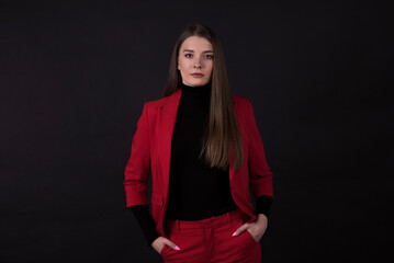 Fototapeta premium Portrait of a businesswoman in a red suit on a black background.