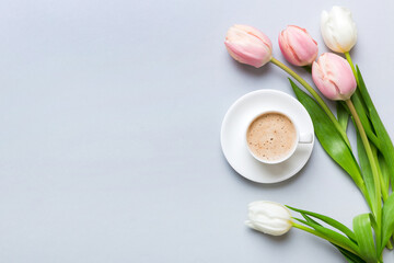 Spring background with flowers, a cup of coffee and a bouquet of pink and white tulips on colored...