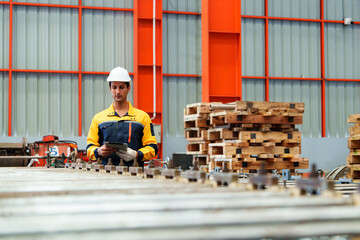 Male worker in metal sheet production line wearing safety helmet and uniform inspecting sheet...