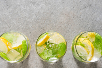 Refreshing lemonade with mint leaves and ice on gray stone table