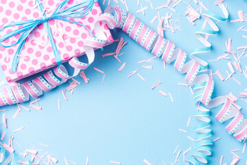 Birthday background with pink dotted gift box, serpentine and confetti on blue background