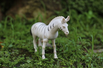 Fototapeta premium White horse or Zebra animal toy with black dots on grassy ground