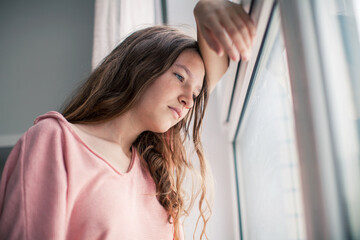 Thoughtful girl looking at window, sad depressed teenager spending time alone at home