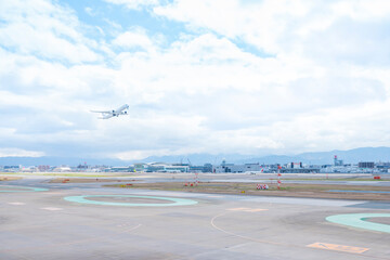 Fototapeta na wymiar 福岡空港の滑走路を離陸して青空に飛んでいく旅客機