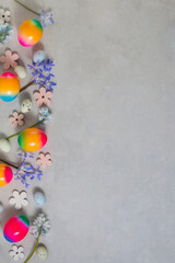 Easter scene with colored rainbow eggs and spring flower on a light gray background.