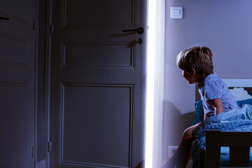 Boy in bedroom look at light coming from the open door