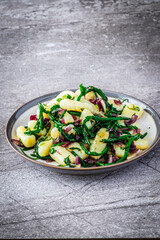 Gnocchi with red onion and sea beans on grey background.