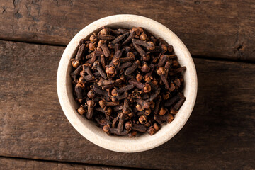 Dried cloves in bowl on wooden table. Close up. Top view